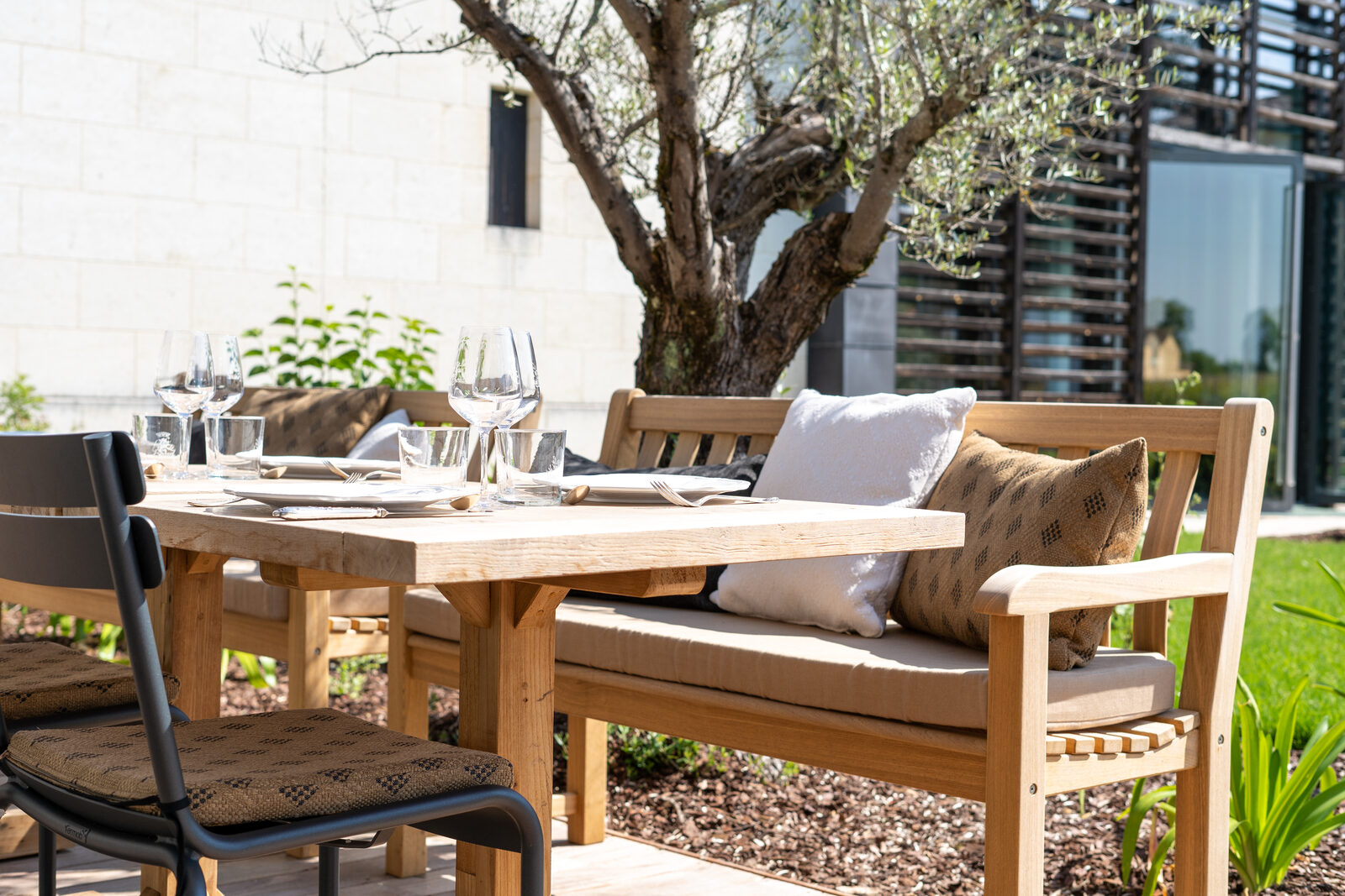 Table dressée en terrasse sous un olivier à Lalande-de-Pomerol.